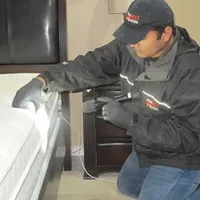 Bed bug inspection technician checking a mattress and bed frame for signs of infestation in Irvine, CA