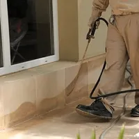 General pest control technician spraying exterior perimeter around a home in Irvine, CA