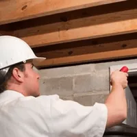 Termite inspection technician checking a basement wall and framing for termite activity in Irvine, CA